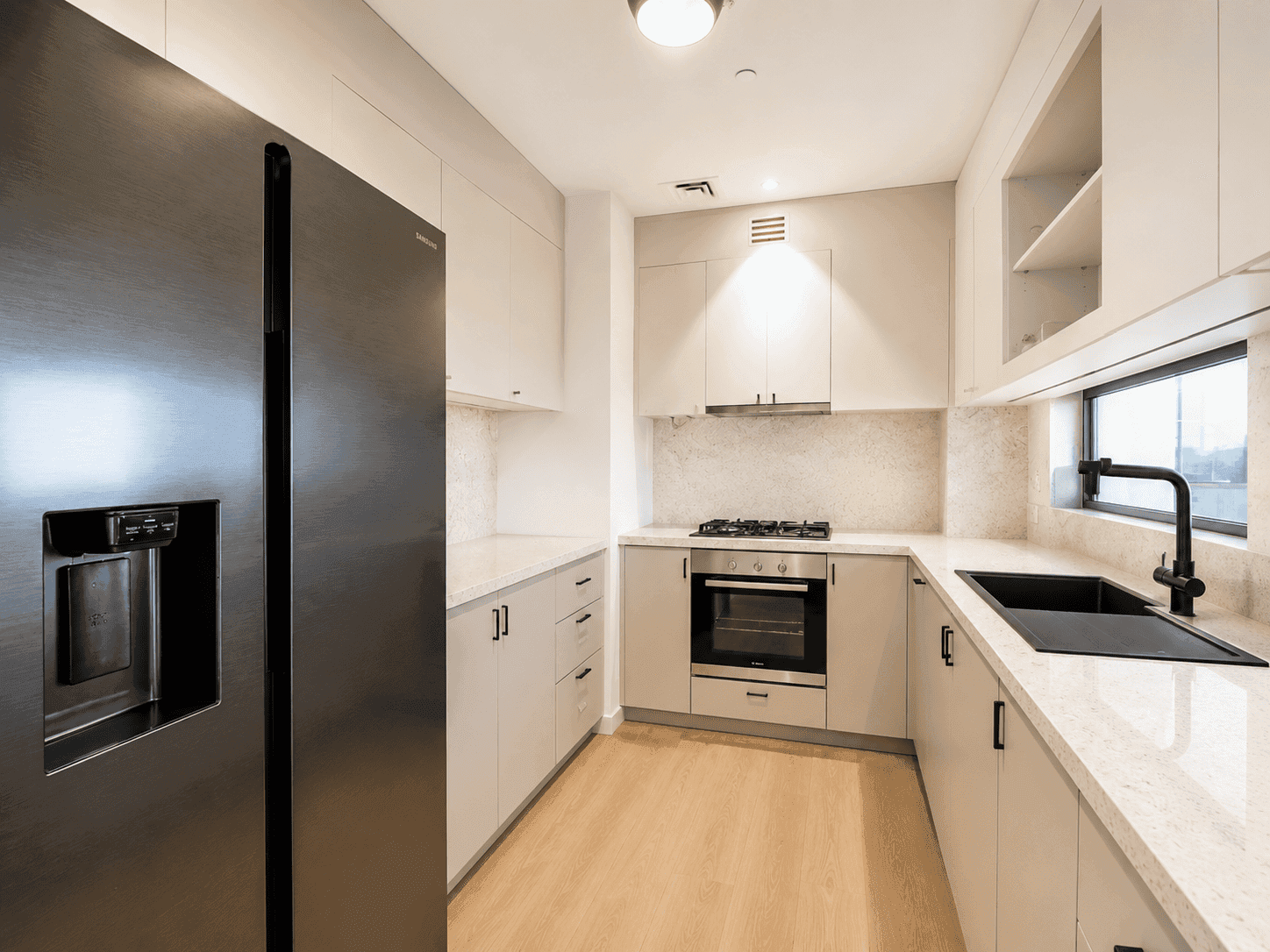 Kitchen renovation in Dubai Hills Estate with greige cabinets, quartz counters, black sink and built-in oven