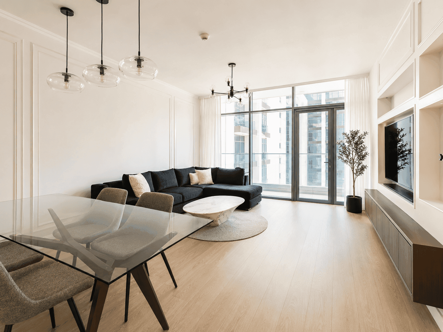 Living room fit-out with dark blue sectional sofa, marble coffee table and floor-to-ceiling balcony doors in Dubai Hills