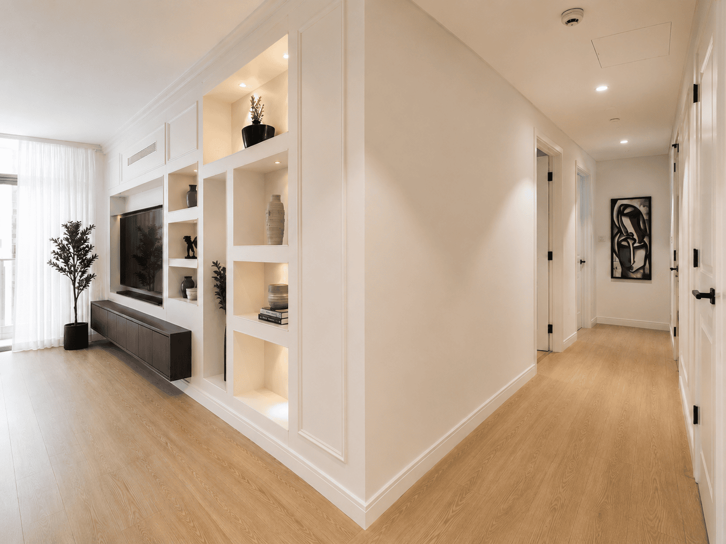 Custom built-in display shelving with lighting niches beside renovated hallway in Dubai Hills apartment