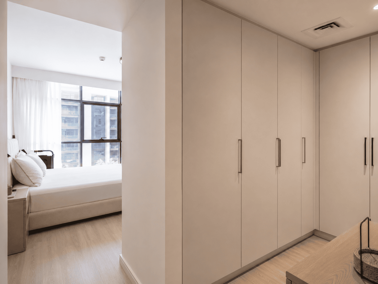 Custom walk-in wardrobe with full-height doors and slim handles connecting to master bedroom in Acacia B