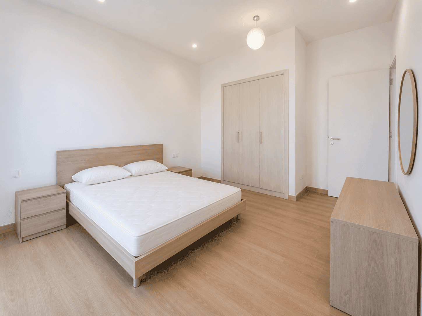 Third bedroom renovation with oak bed, built-in wardrobes and round mirror in Victory Heights villa, Dubai