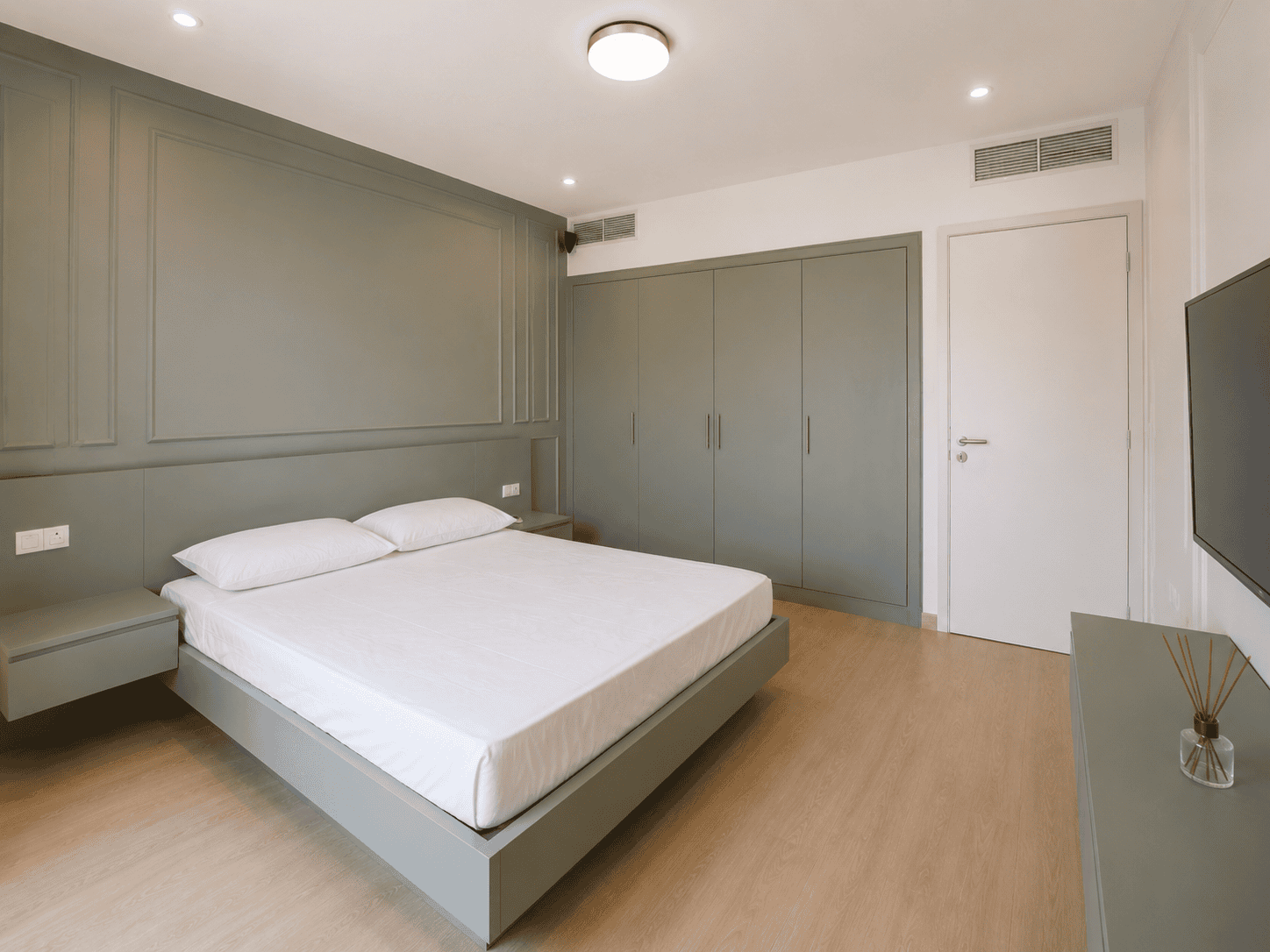 Sage green bedroom with matching built-in wardrobes, panelled headboard wall and dresser in Victory Heights villa
