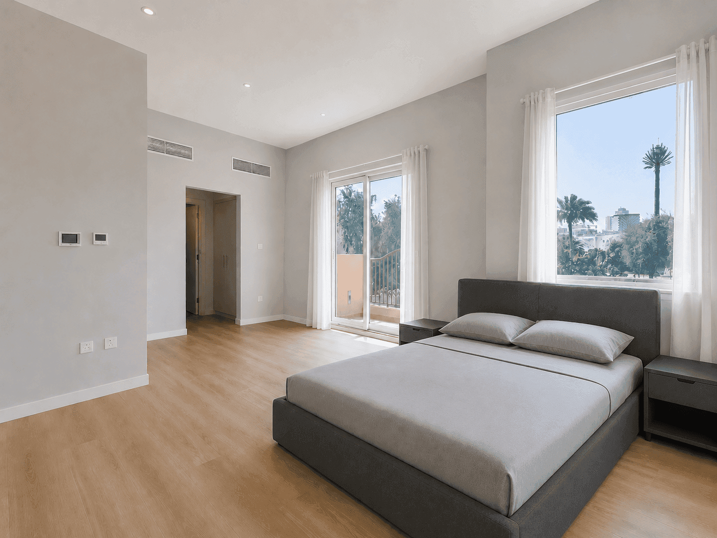 Master bedroom renovation with grey limewash walls, upholstered bed and palm views in Victory Heights villa, Dubai