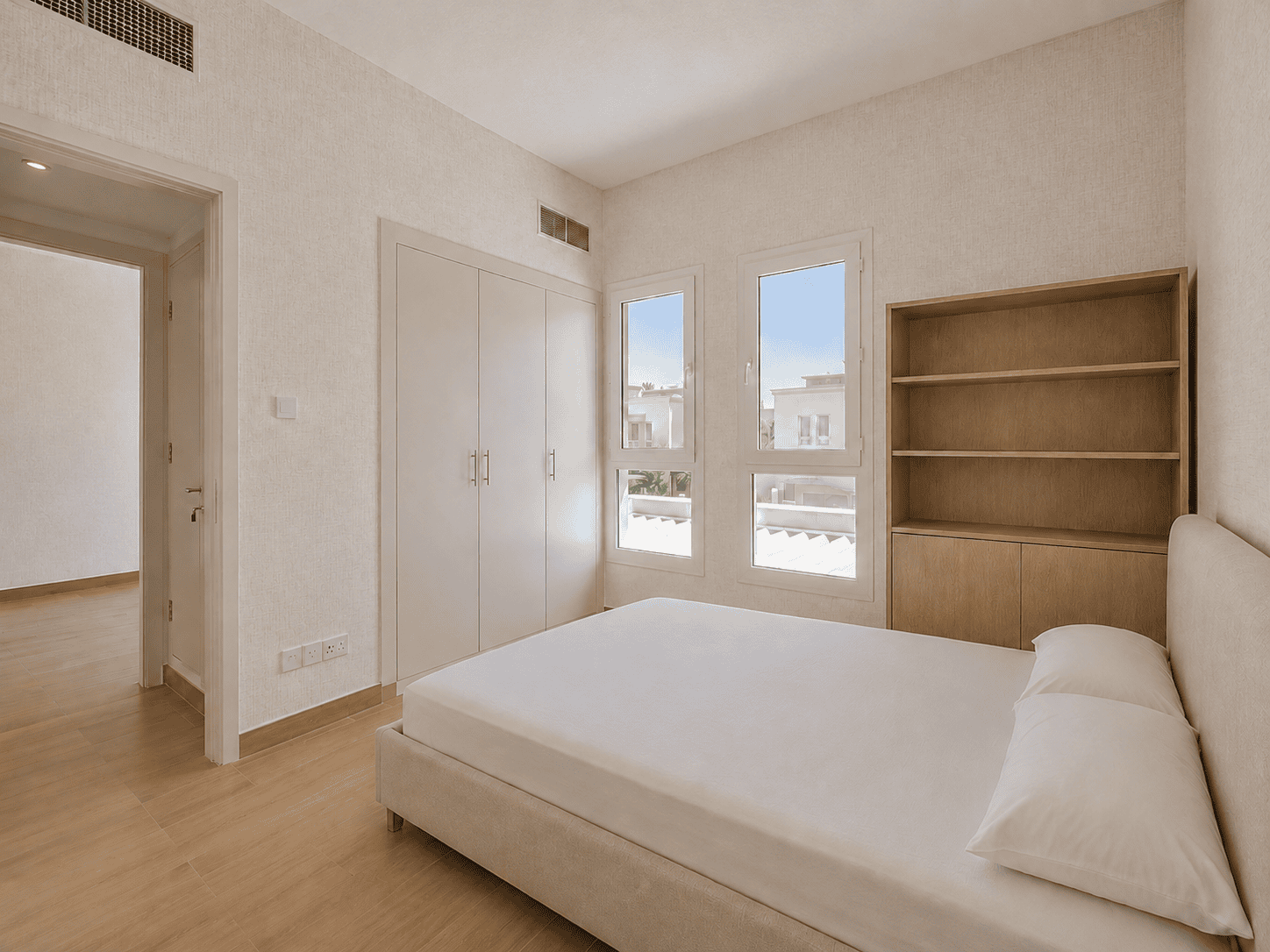 Bedroom three with built-in wardrobes, oak display shelving and community views in renovated Lakes villa
