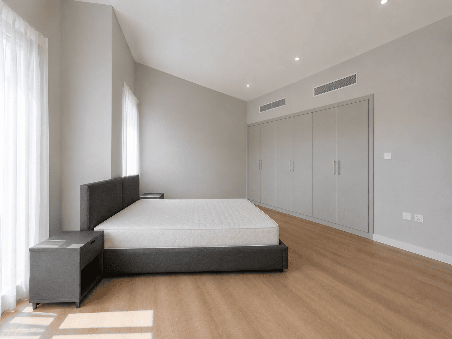 Master bedroom with wall-to-wall built-in grey wardrobes and vaulted ceiling in renovated Victory Heights villa