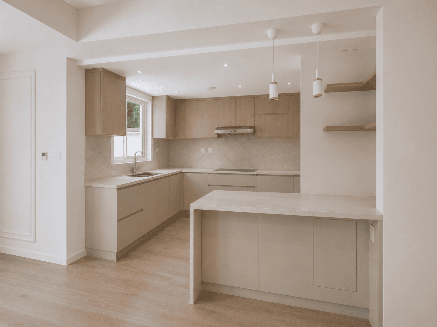 Open kitchen with breakfast counter, pendant lights and floating oak shelves in renovated Lakes villa, Dubai