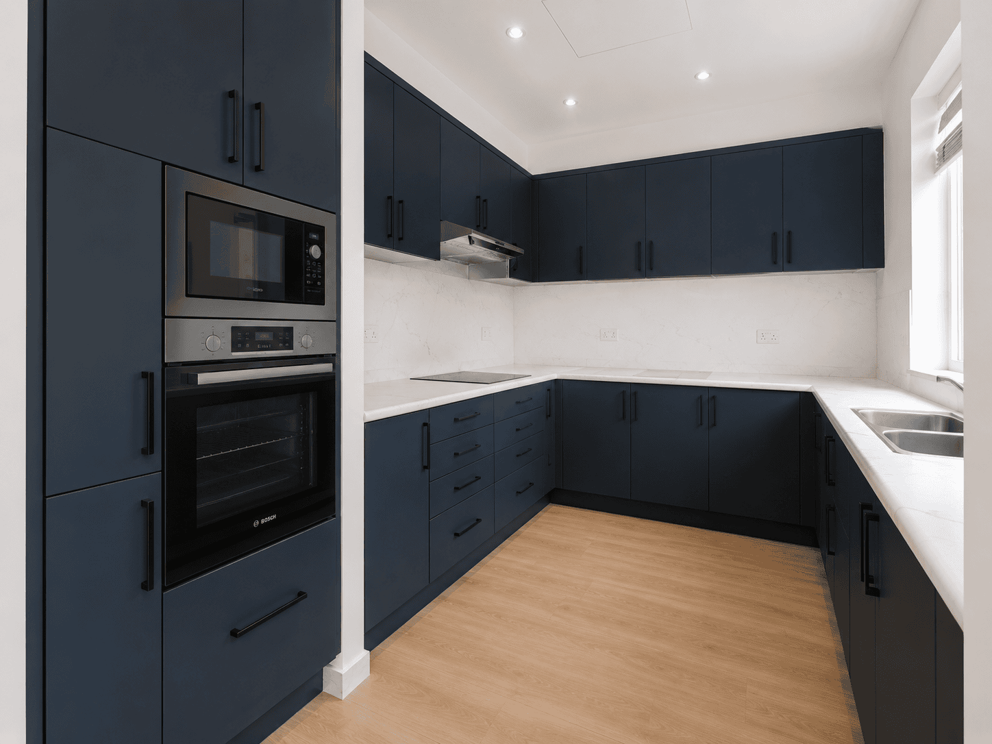 Navy blue shaker kitchen renovation with marble-look quartz counters and Bosch appliances in Victory Heights, Dubai