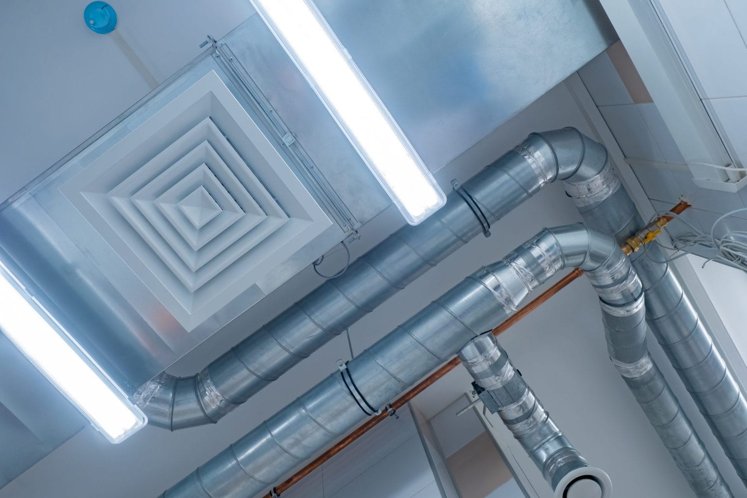 Ductwork and copper chilled water pipework above a suspended ceiling