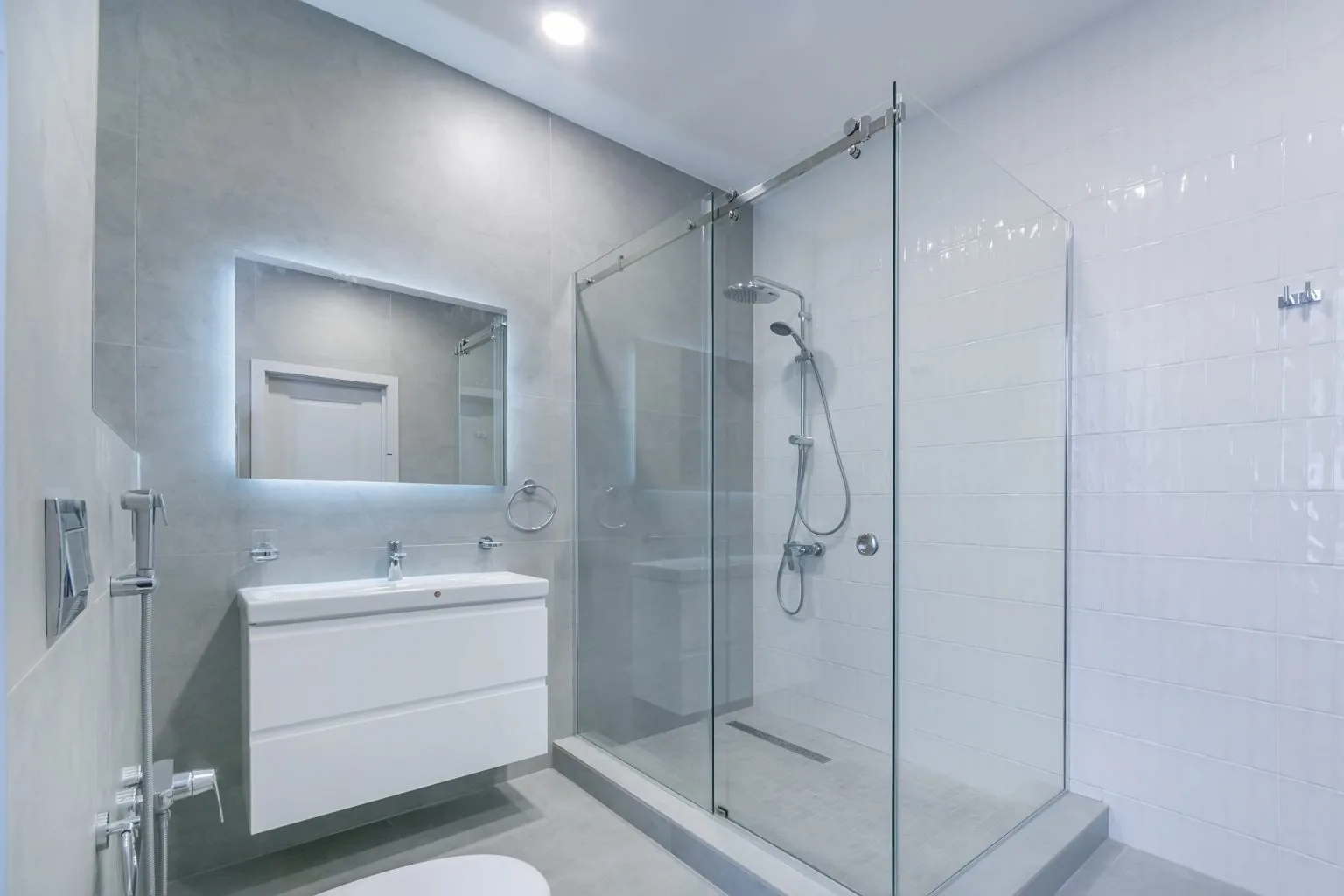 Frameless glass shower enclosure with a sliding door and rain shower head in a Dubai bathroom renovation