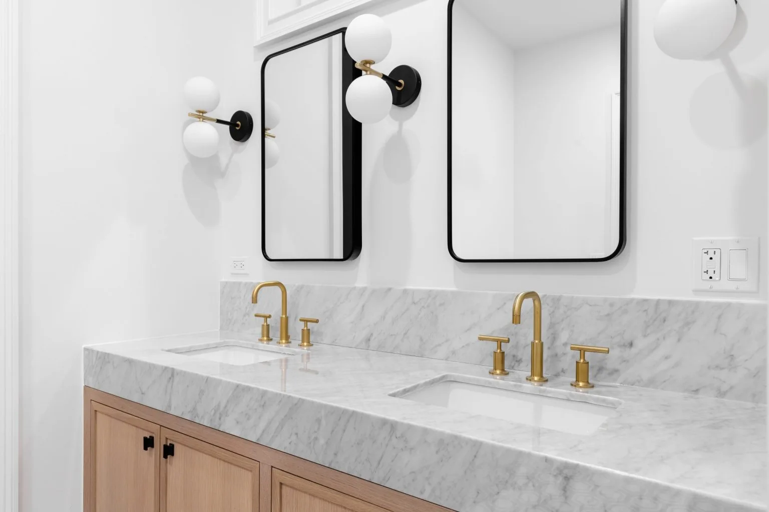 White marble double vanity with brushed brass tapware and twin black framed mirrors in a Dubai bathroom