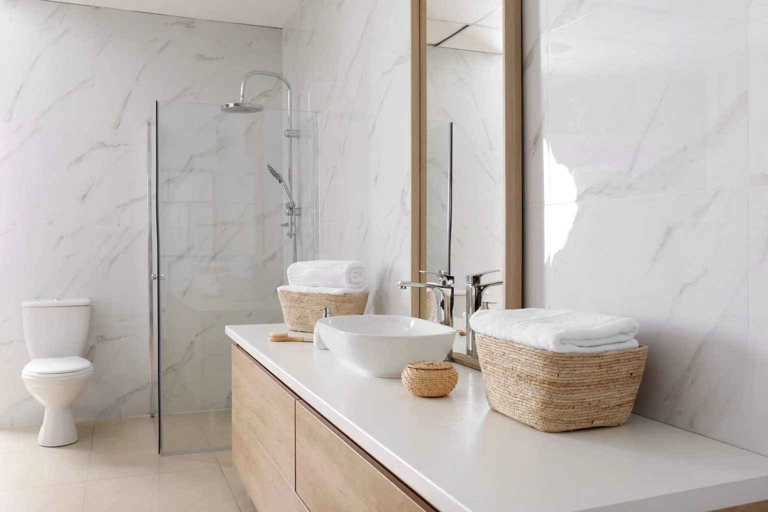 Marble bathroom with a timber vanity, vessel basin and walk in glass shower by a bathroom renovation company in Dubai