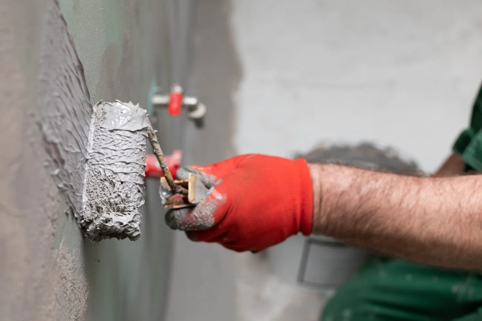 Applying a cementitious waterproofing membrane by roller to a bathroom wall in Dubai before tiling