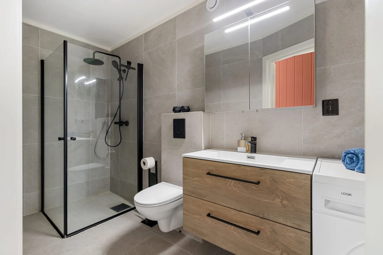 Compact modern bathroom remodeling in Dubai with a black framed glass shower and oak wall hung vanity