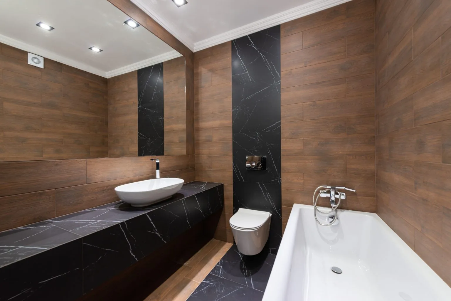 Wood look and black marble wall panelling in a Dubai bathroom tiling and flooring project