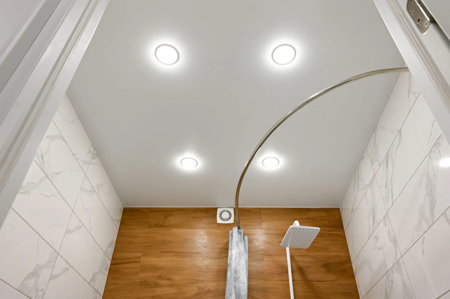 Bathroom false ceiling with recessed LED downlights and concealed extraction above marble walls in Dubai