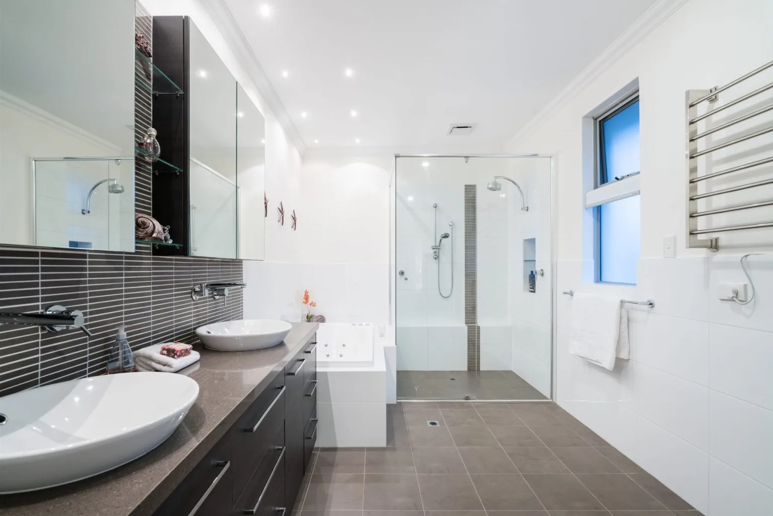 Completed Dubai bathroom remodel with a dark twin basin vanity, frameless walk in shower and built in bathtub