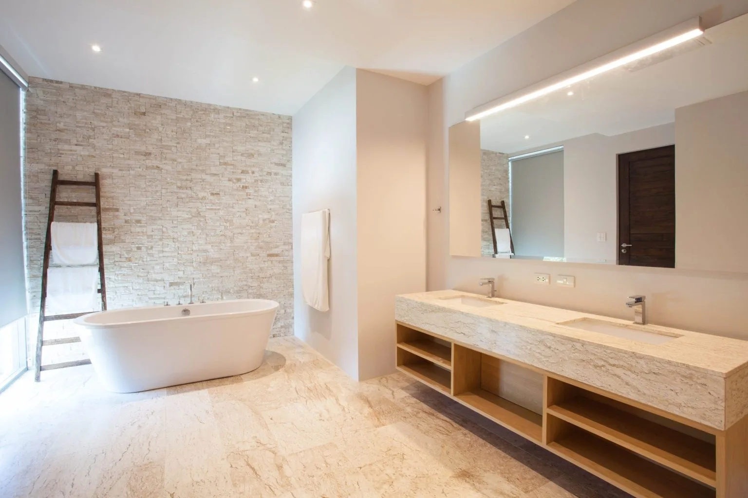 Freestanding bathtub against a stone clad feature wall in a Dubai villa bathroom renovation