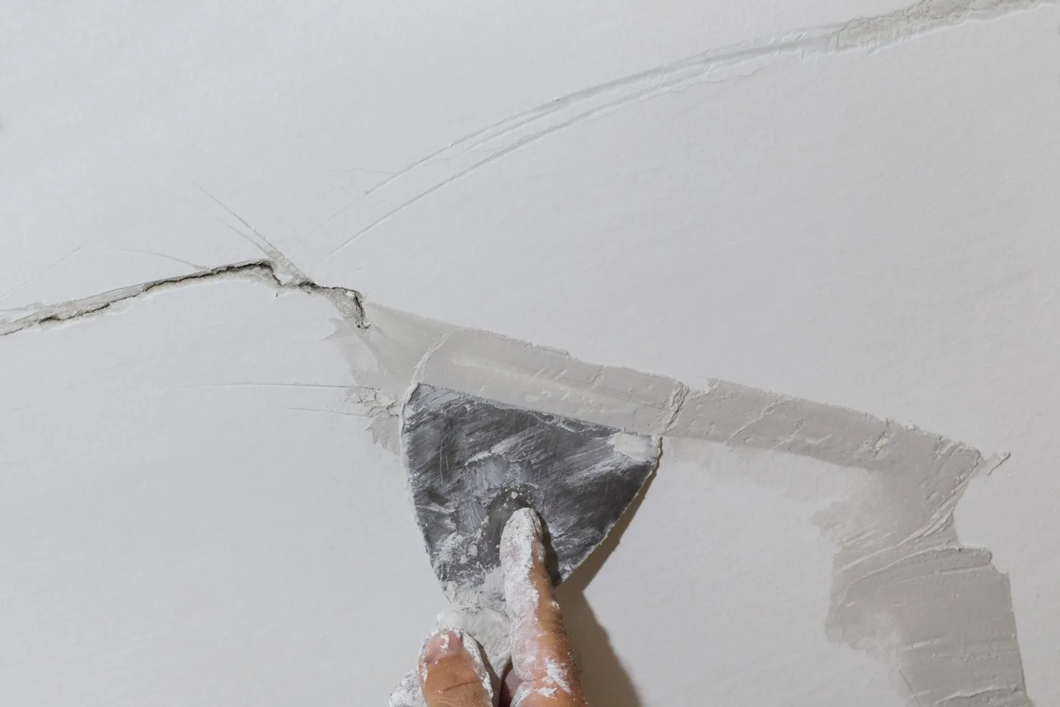Filling and smoothing a ceiling crack before repainting during a Dubai ceiling repair
