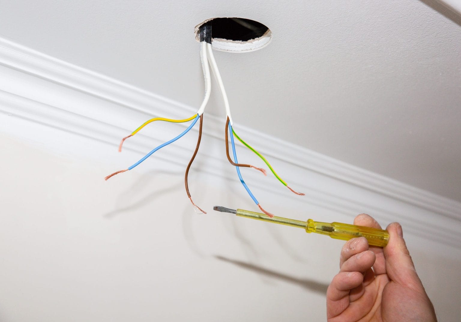 Screwdriver terminating cables at a ceiling rose