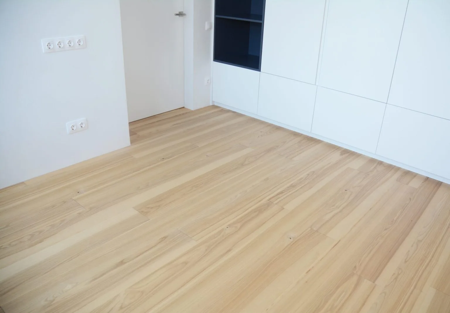Light engineered wood flooring in a modern Dubai home with white cabinetry