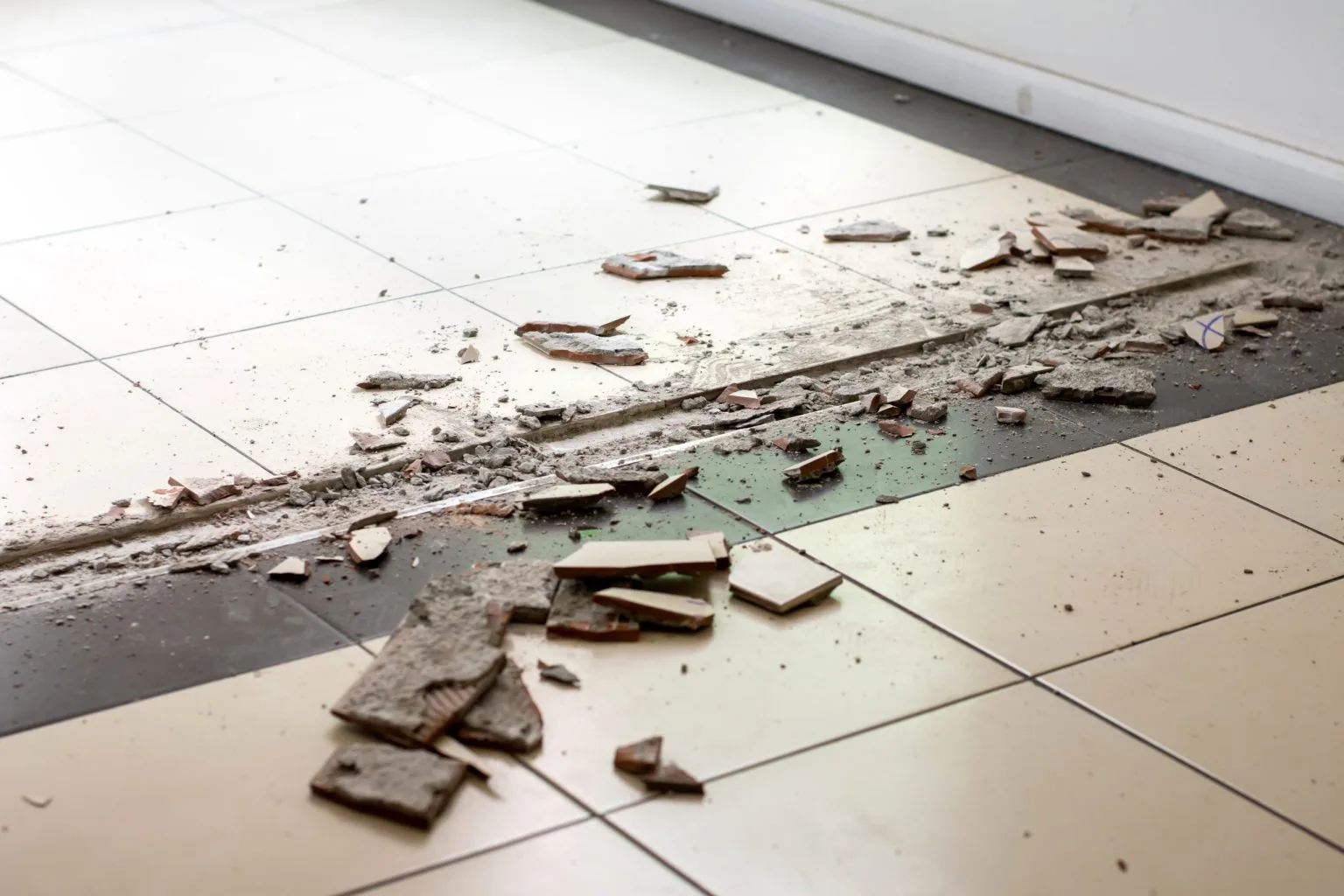 Floor tiles lifted and old adhesive broken out during a tile removal job in Dubai