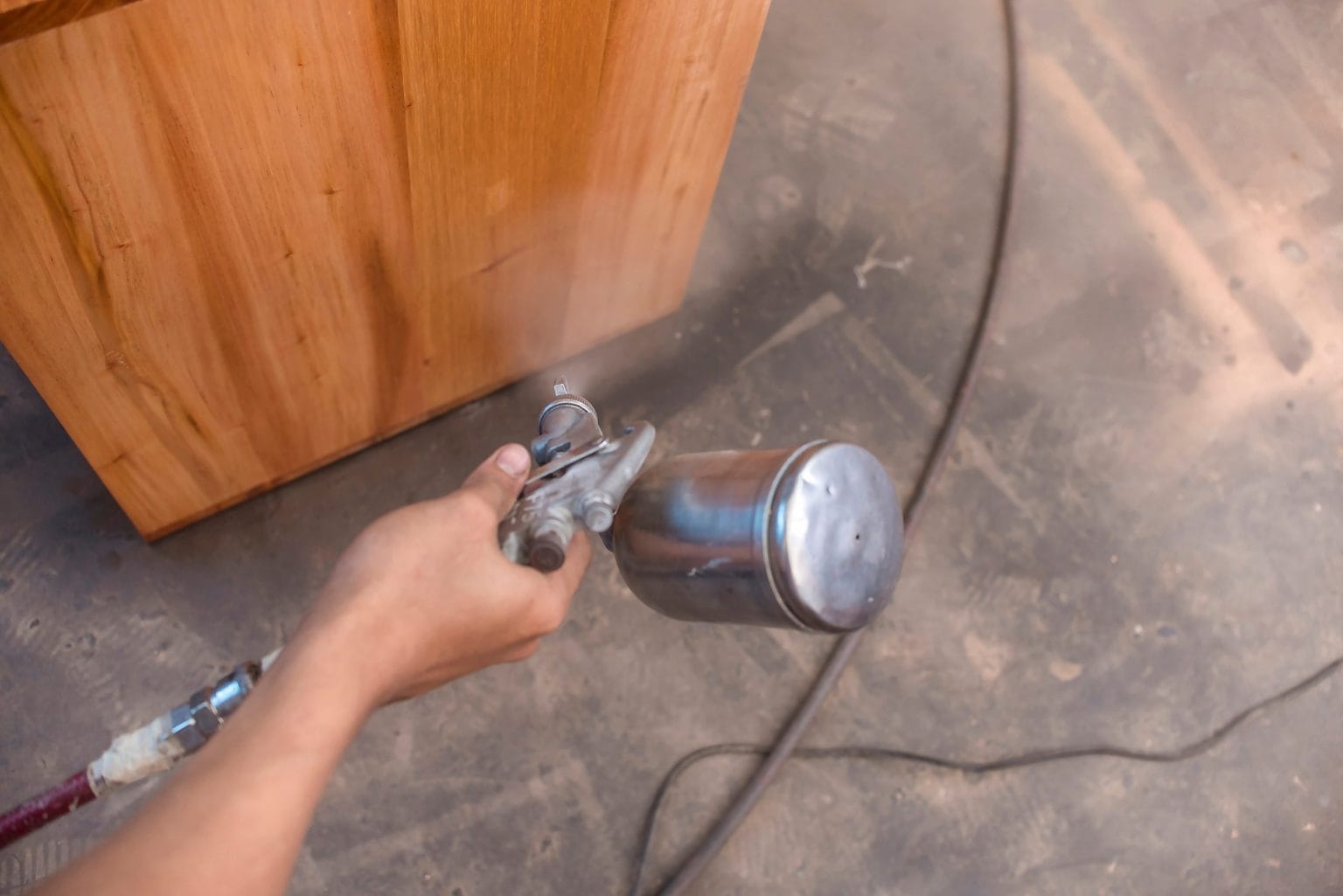 Spray gun laying a lacquer coat across a timber panel