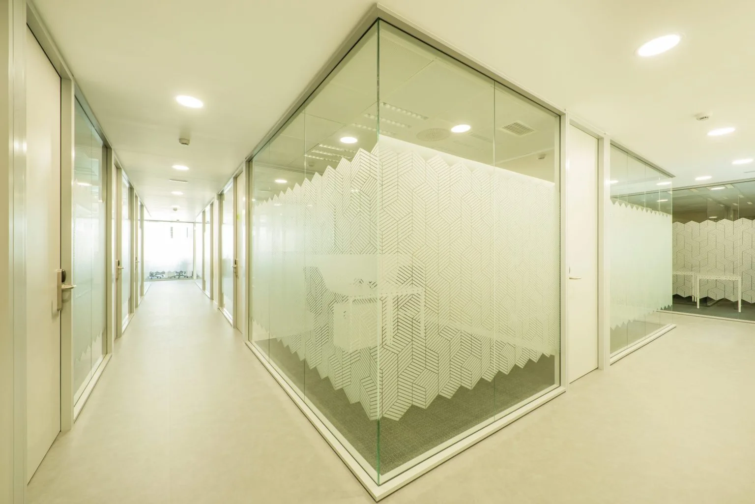 Etched decorative glass office partition along a Dubai corridor