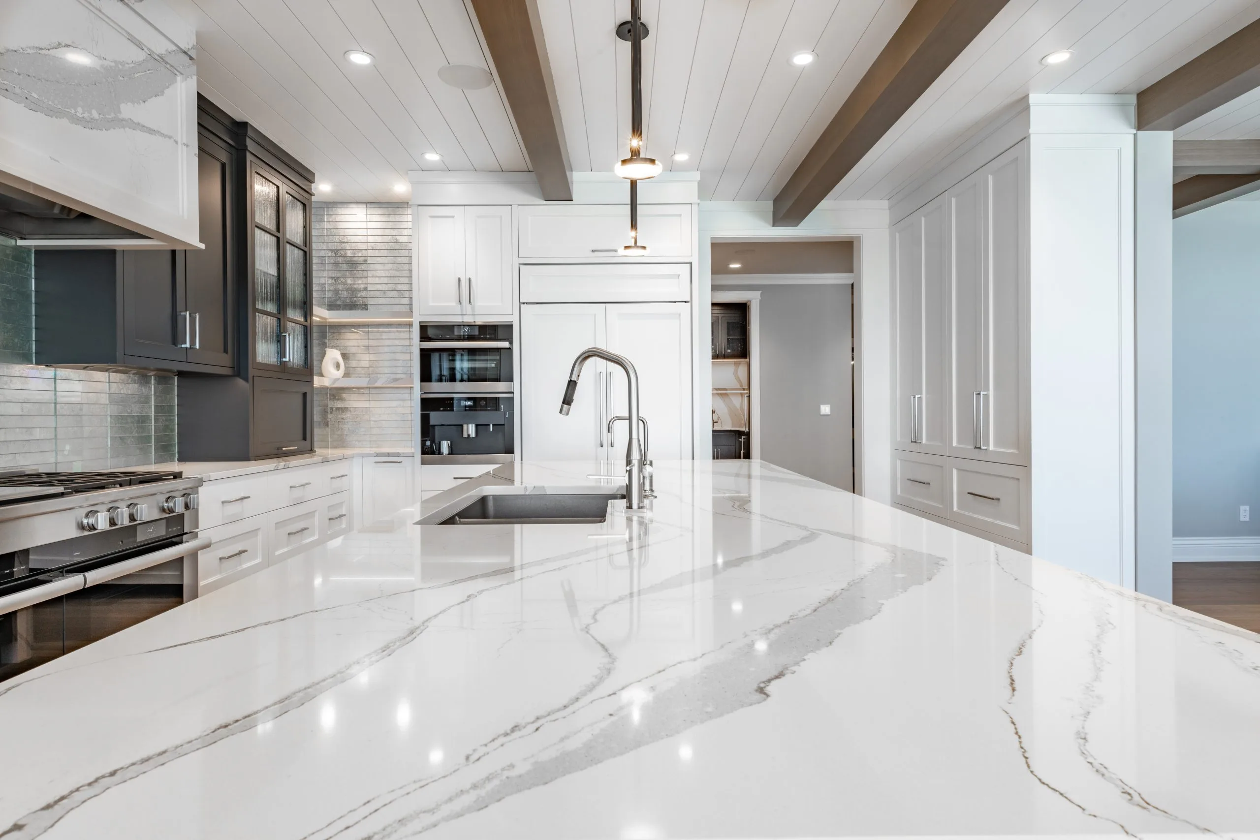 Quartz countertop waterfall edge and mixer tap detail from a kitchen remodeling Dubai project
