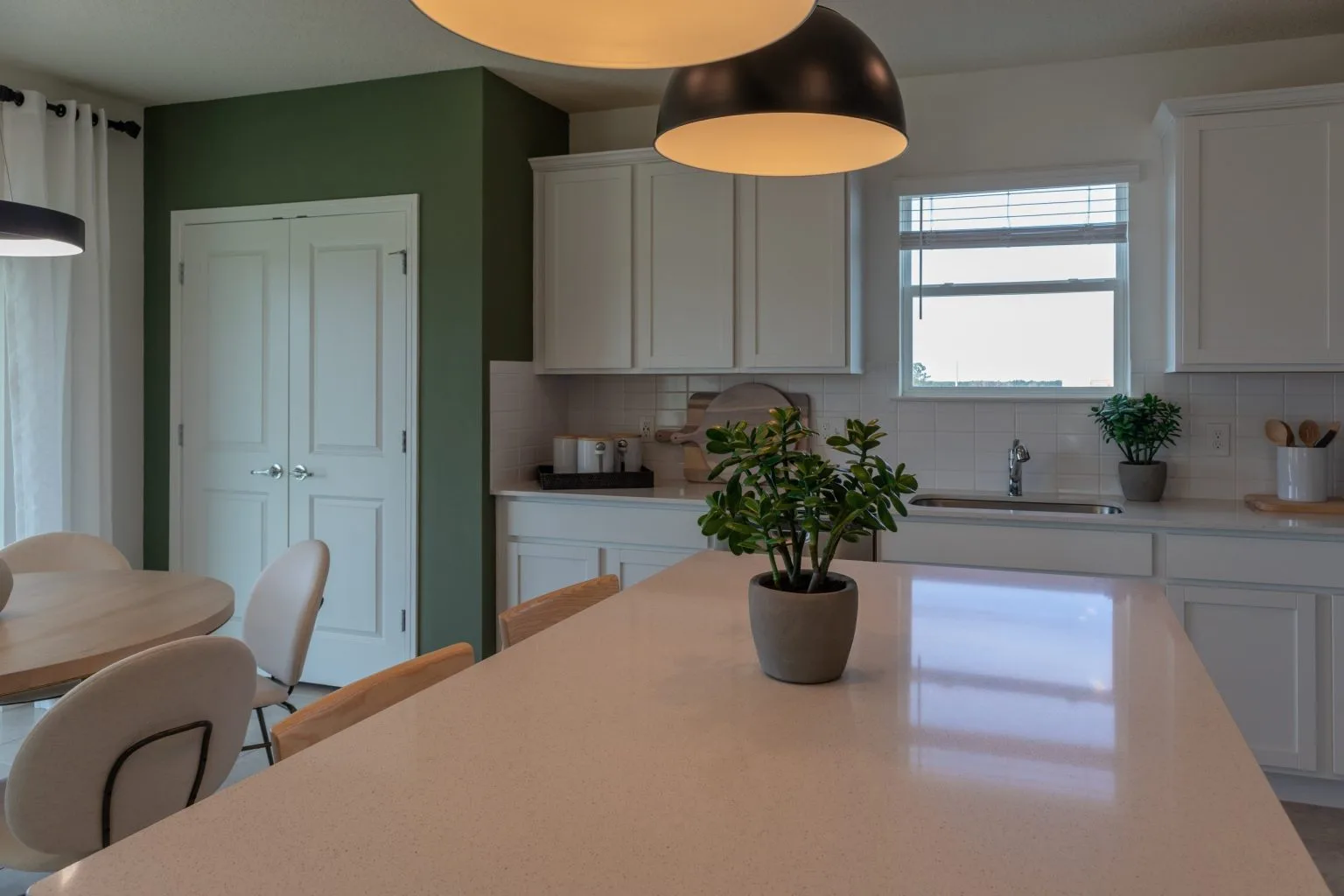 Villa kitchen in white with a deep green accent wall and a timber worktop run