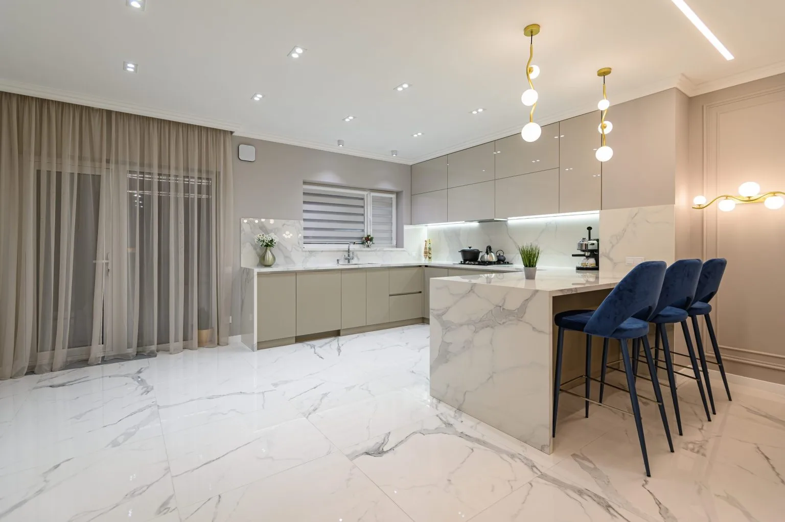 Marble peninsula with bar stools in an apartment kitchen opening onto the living room