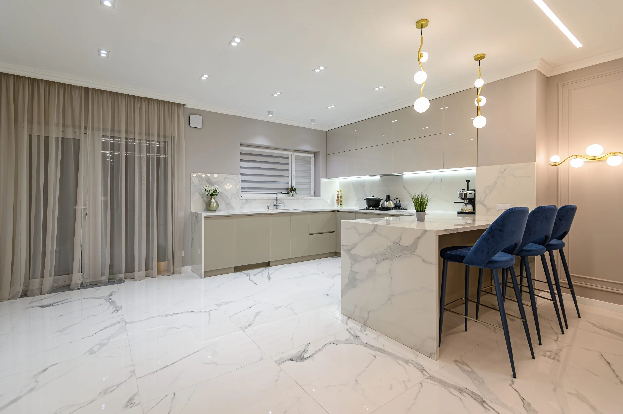 Modular kitchen Dubai in cream gloss with a marble countertop peninsula and bar seating