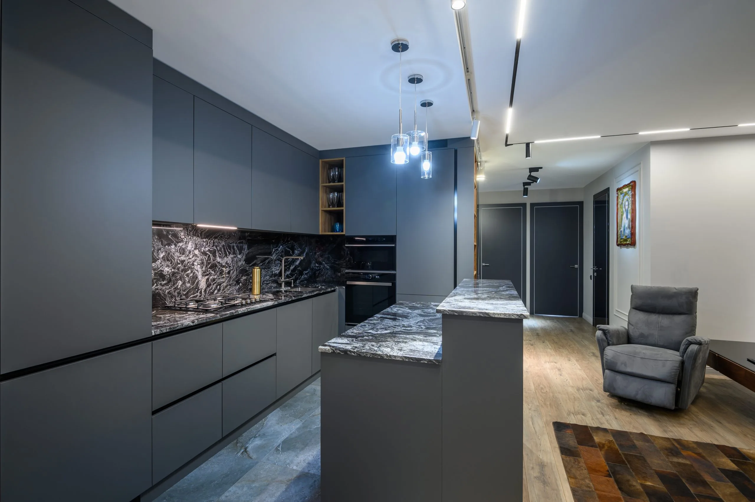 Dark matte kitchen cupboards with a veined marble countertop and backsplash in a Dubai kitchen remodel