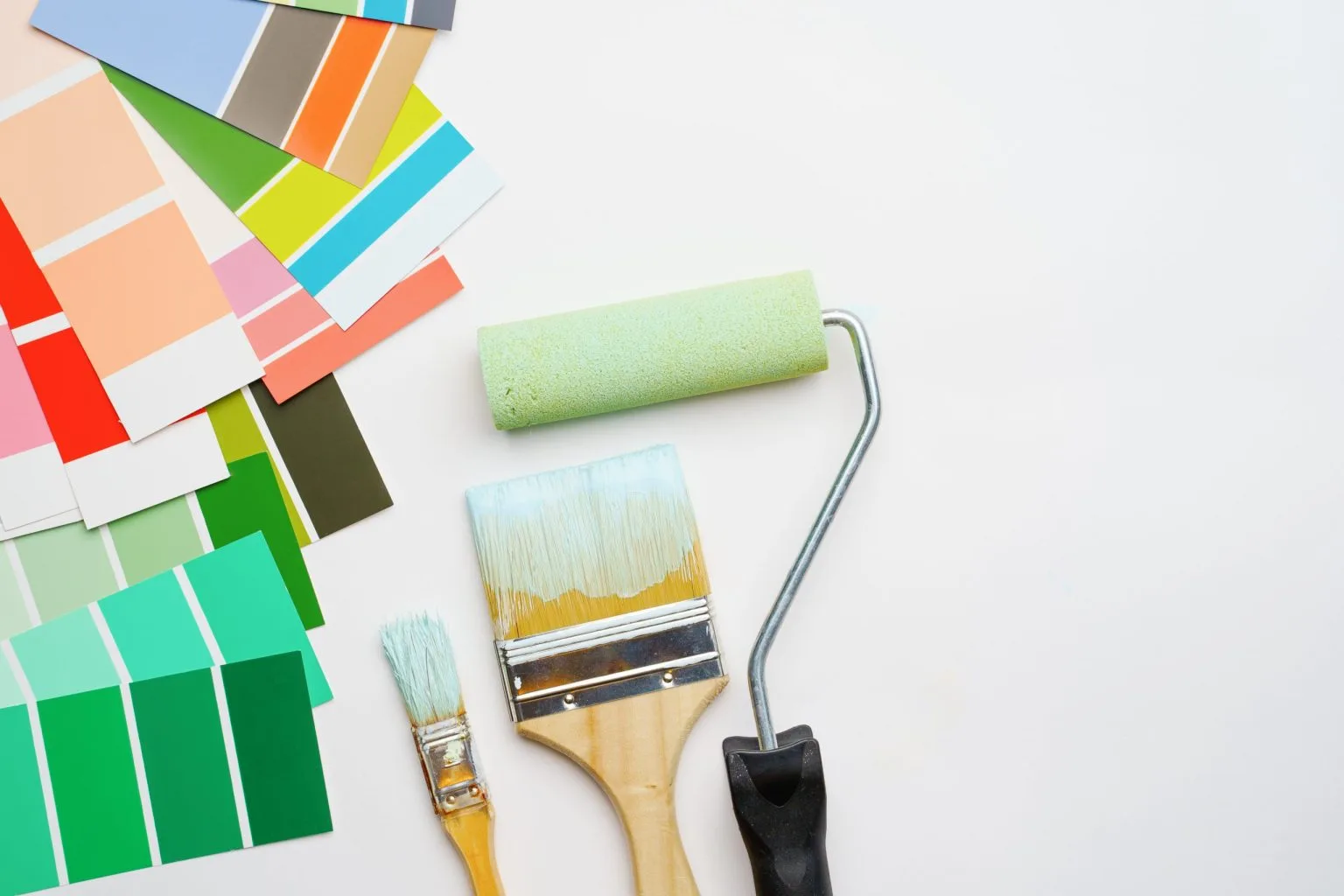 Paint colour swatch fan, brushes and roller laid out for choosing a shade in Dubai