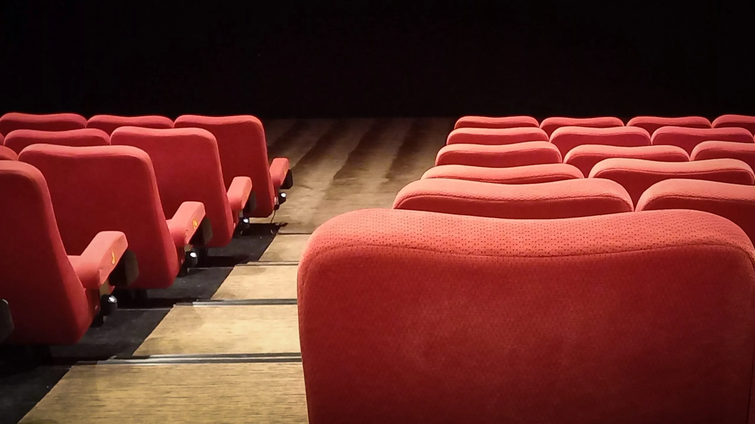 مقاعد سينما حمراء فاخرة بممر مركزي بتشطيب خشبي في صالة بدبي