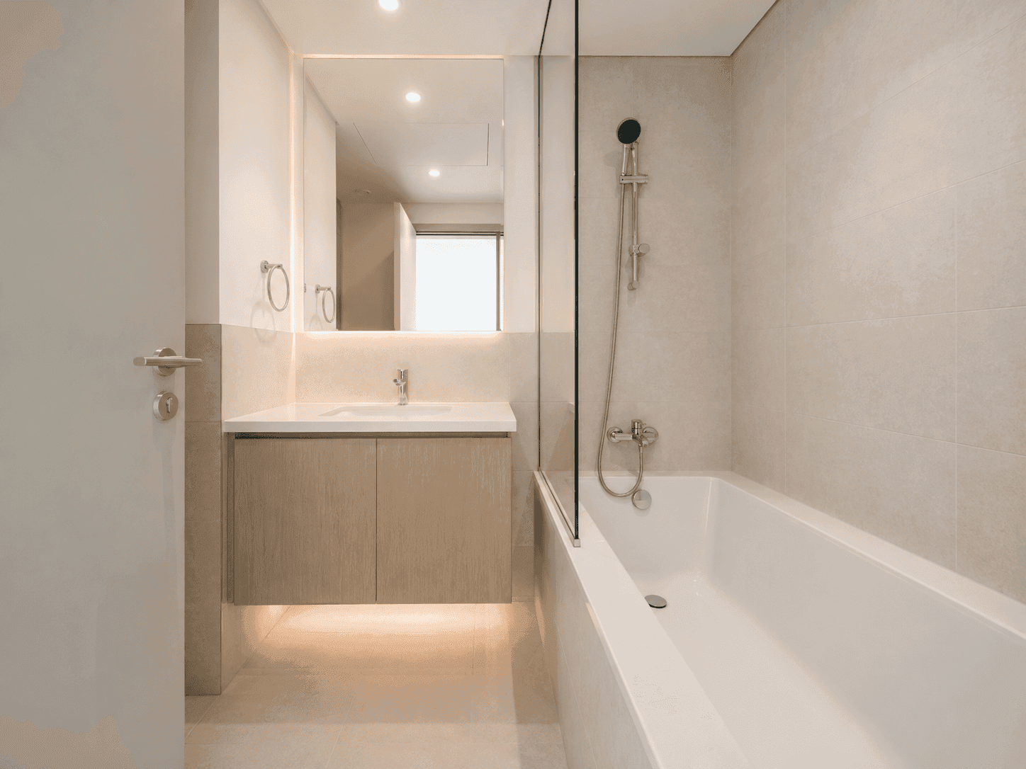 Bathroom renovation with built-in bathtub, glass screen, backlit mirror and floating vanity in Creek Harbour apartment