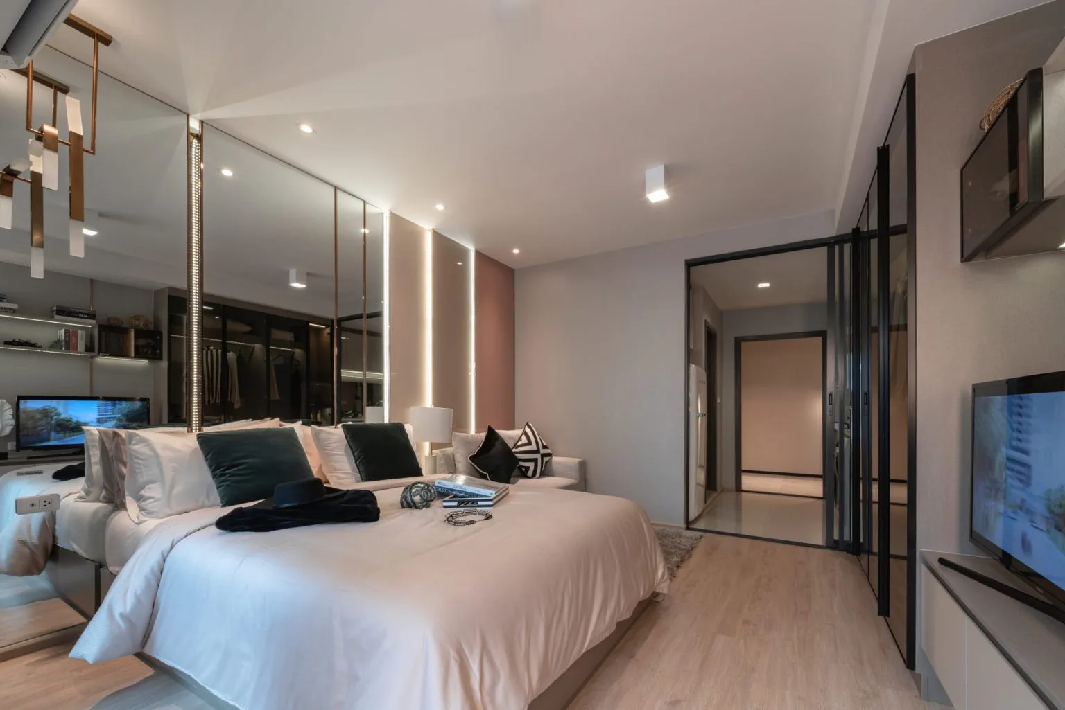Compact apartment bedroom with a full-height mirrored feature wall and wall-mounted television