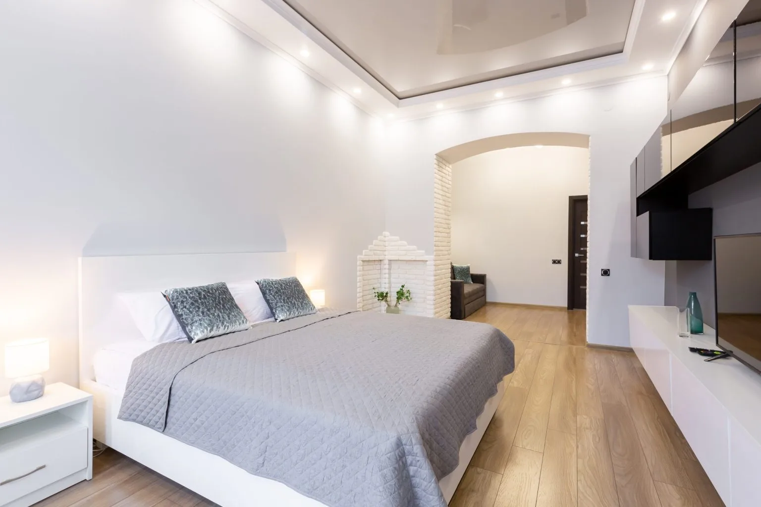 Bedroom gypsum false ceiling with recessed downlights and a brick feature arch