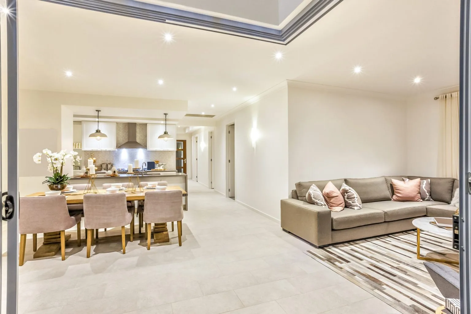 Open-plan living and dining space with the kitchen beyond and large-format floor tiles