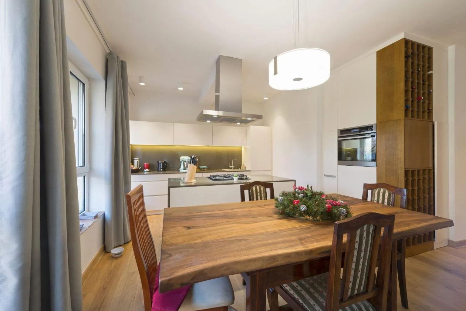 Dining area beside the kitchen with a solid timber table and a fluted timber screen