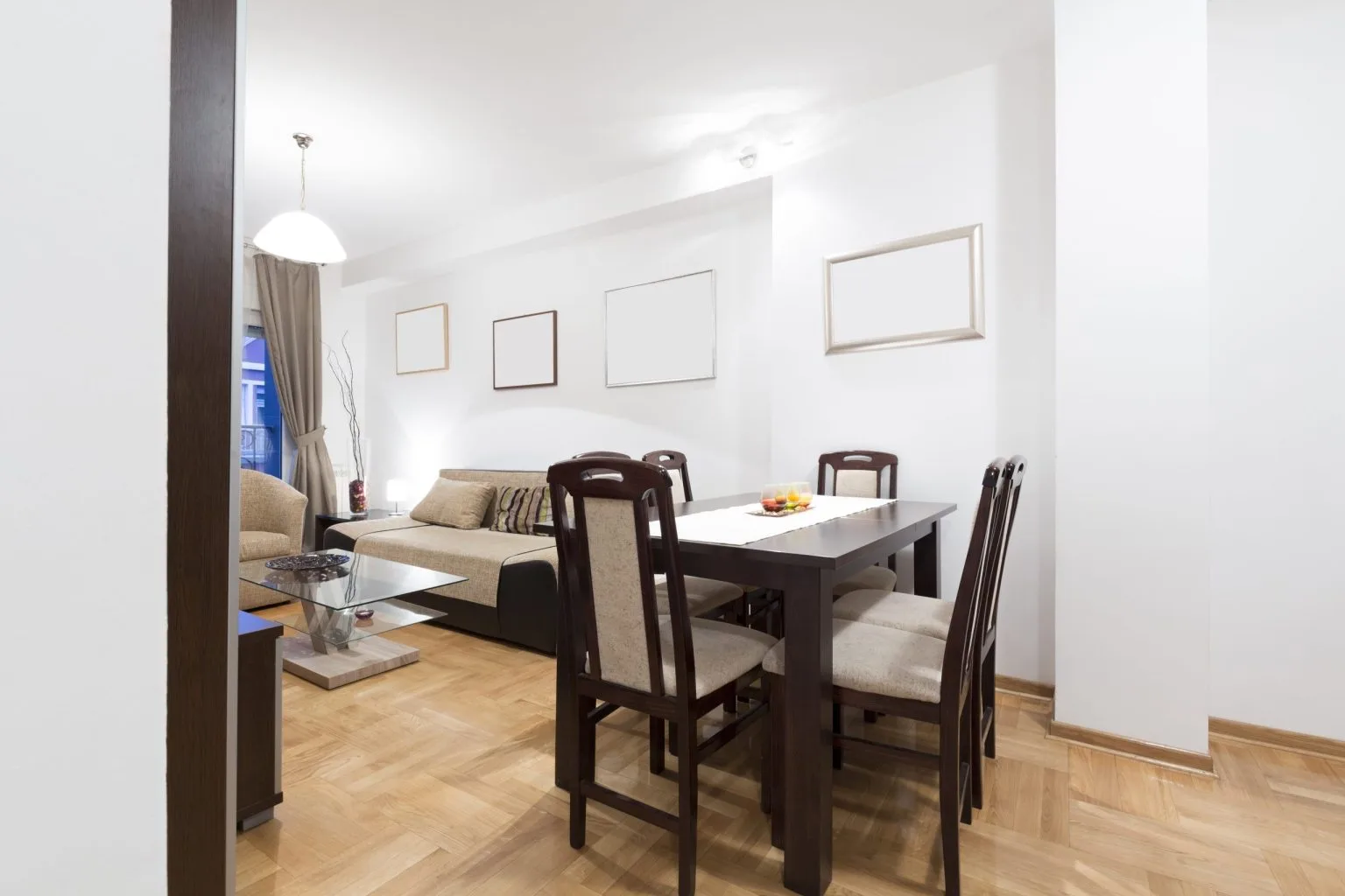 Apartment dining area laid with warm timber parquet running through to the living room