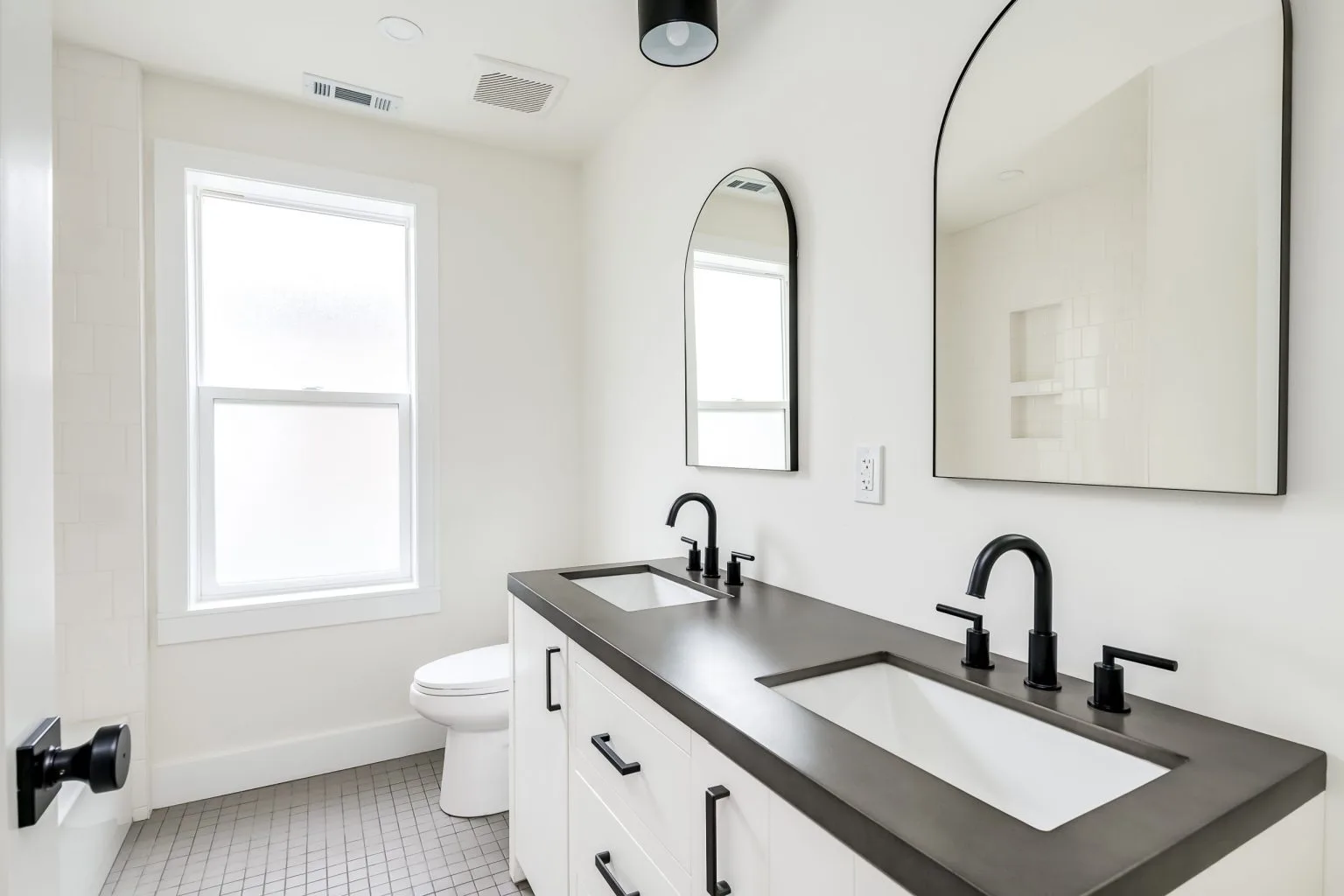 Two arched black-framed mirrors fixed above a double vanity in Dubai