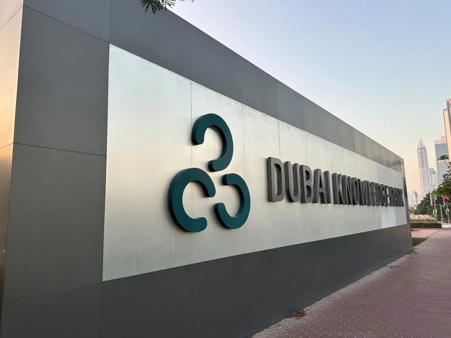 Brushed metal three-dimensional logo and letters mounted on a clad building entrance wall in Dubai