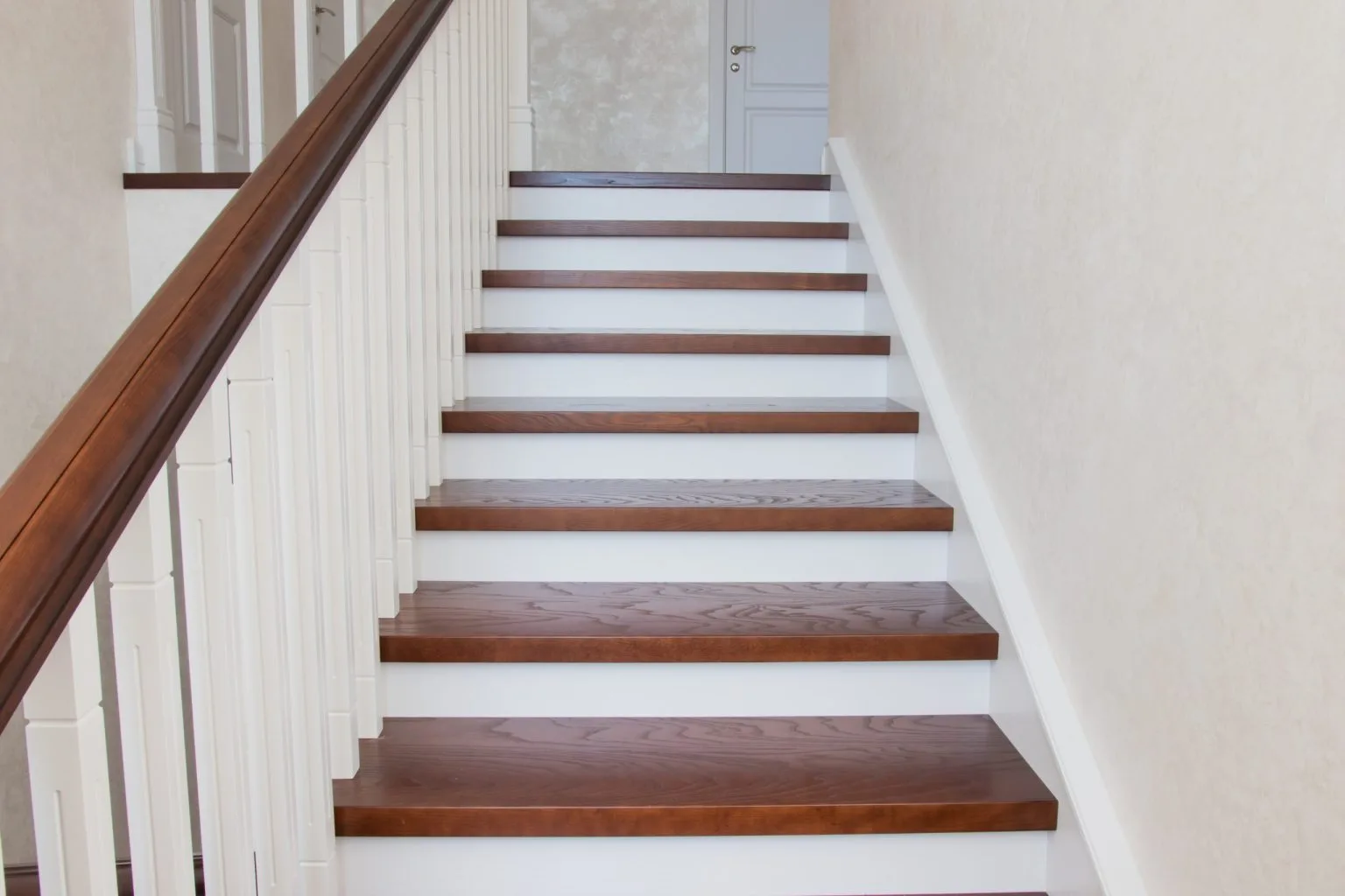 Straight timber staircase with white risers and a dark stained handrail in a Dubai home