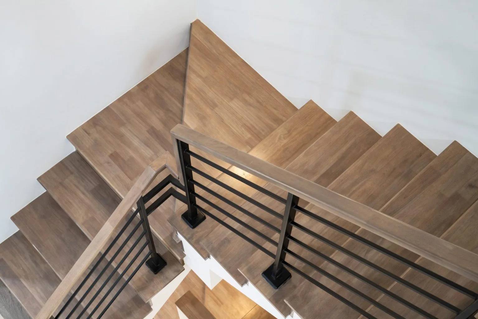 Timber staircase treads with a black metal bar balustrade seen from above