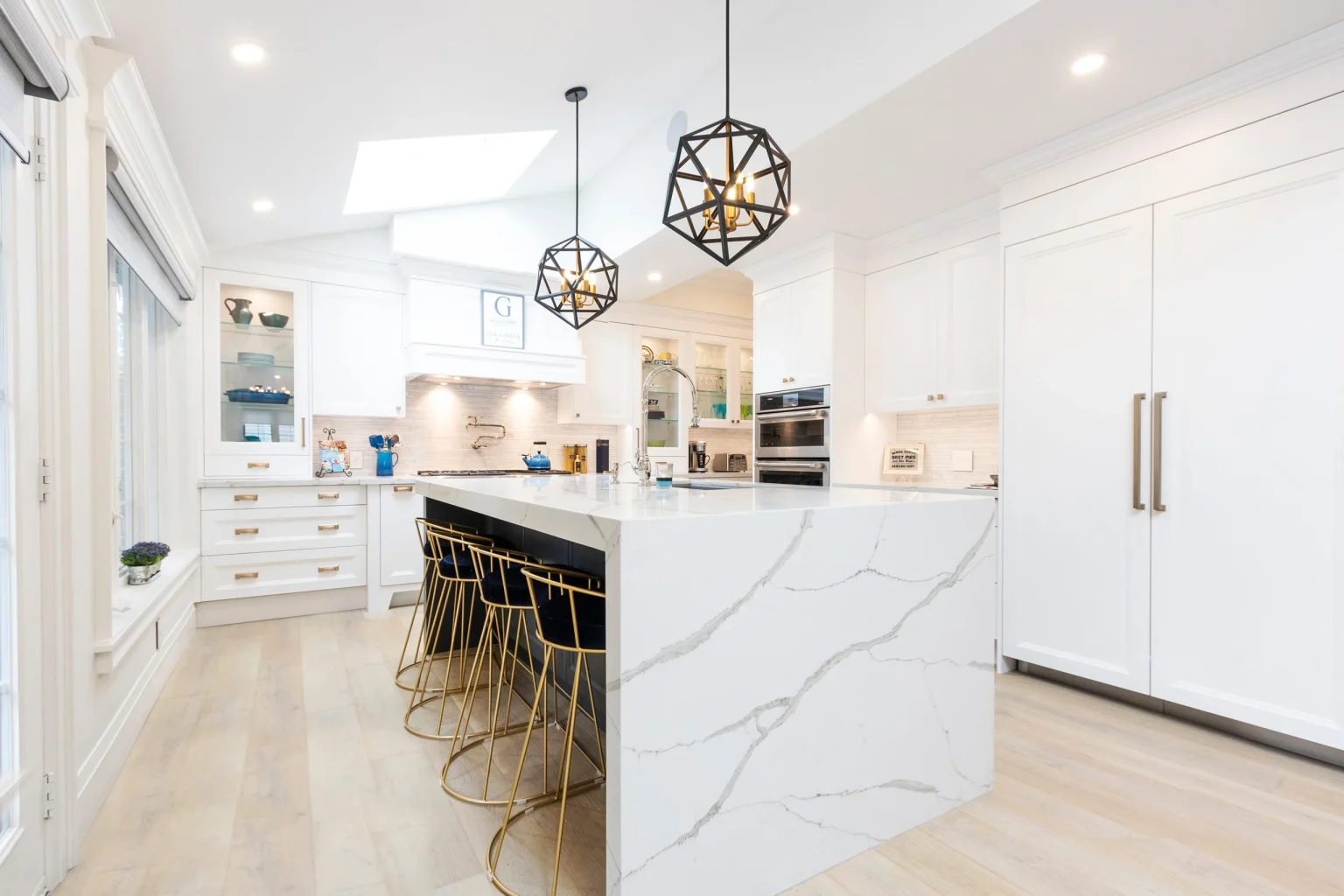 White quartz waterfall island with veined stone in a Dubai kitchen