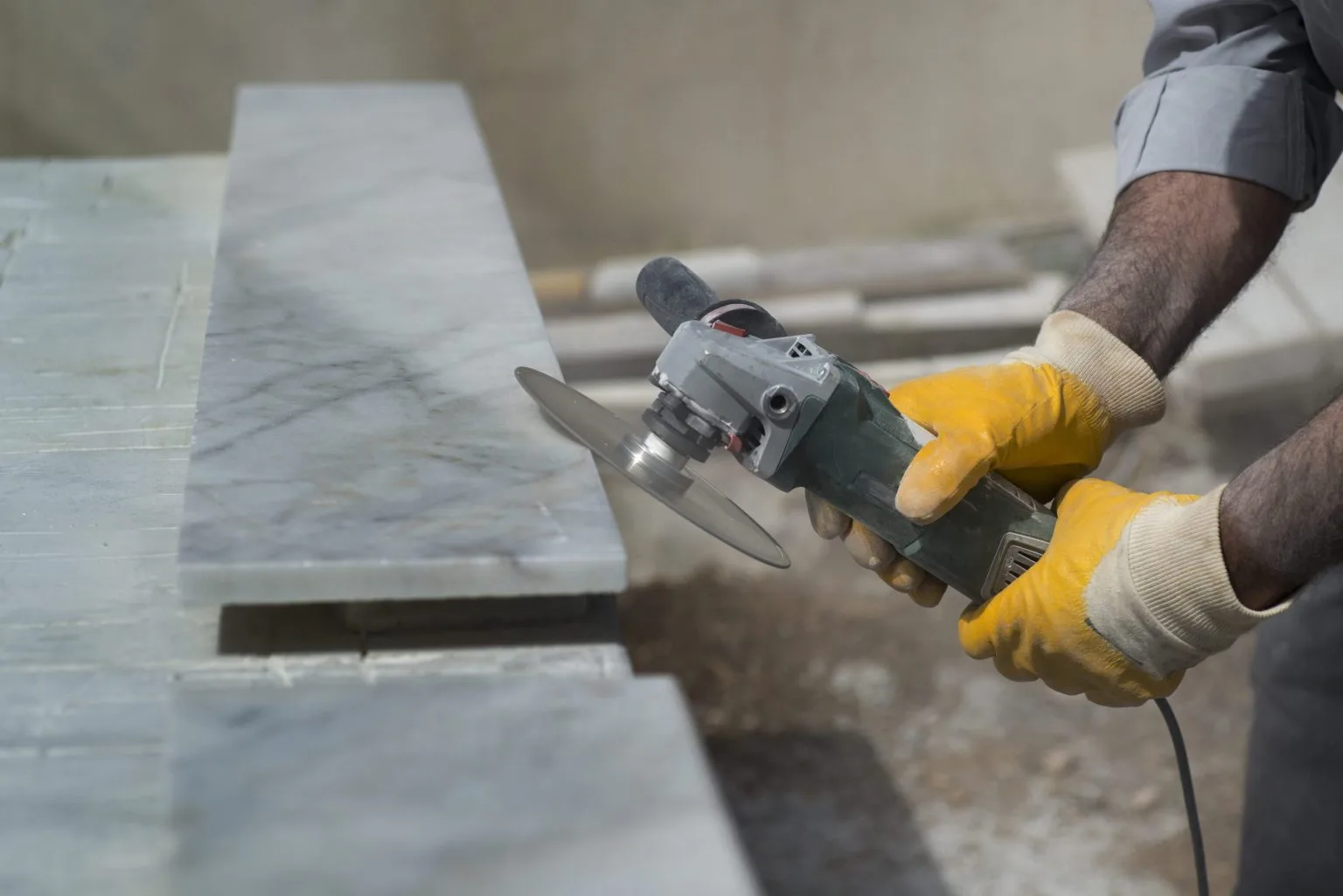Angle grinder dressing the polished edge of a stone slab in the workshop