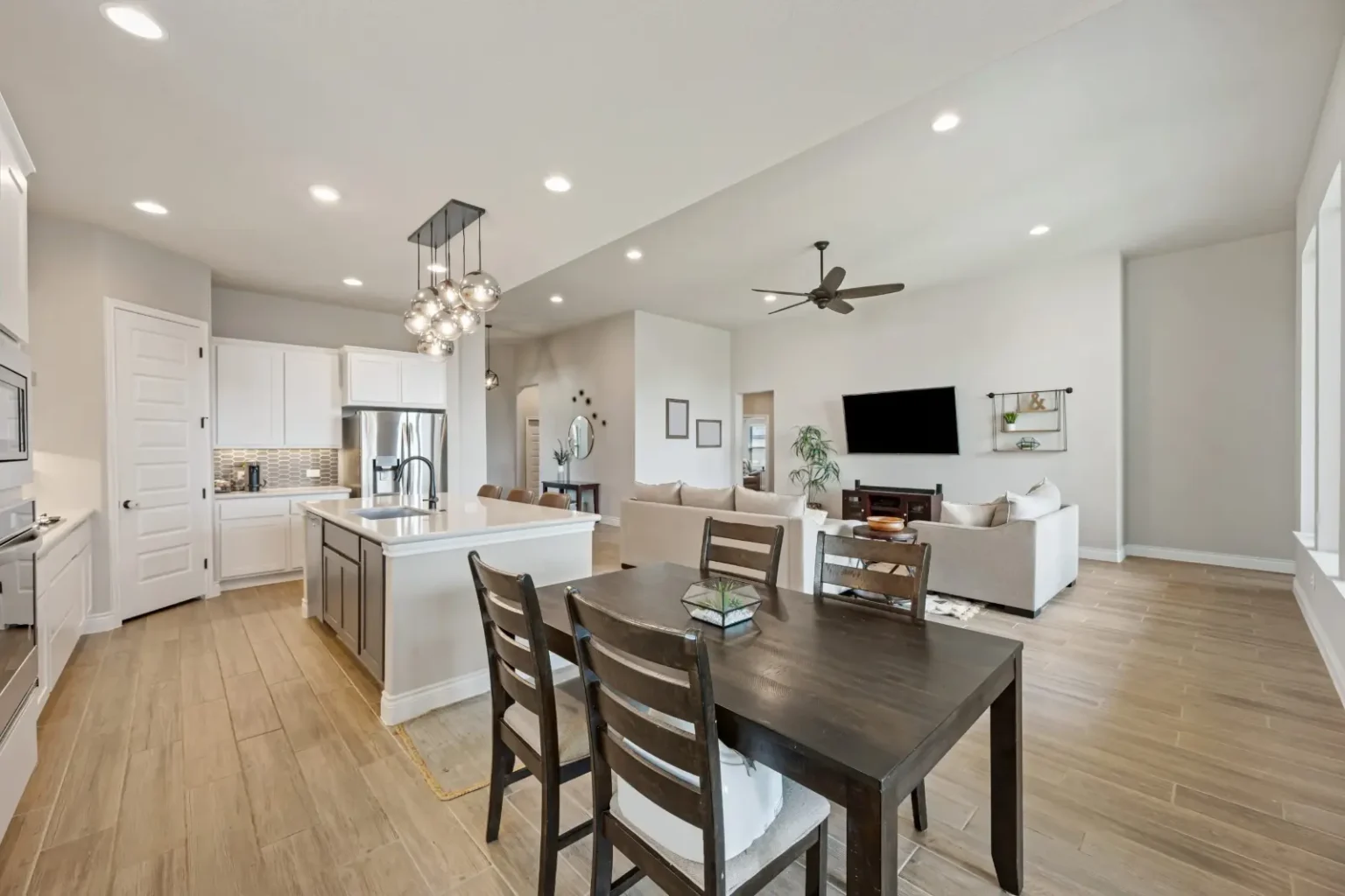 Open-plan dining area with a dark timber table and a cluster of glass pendants over it