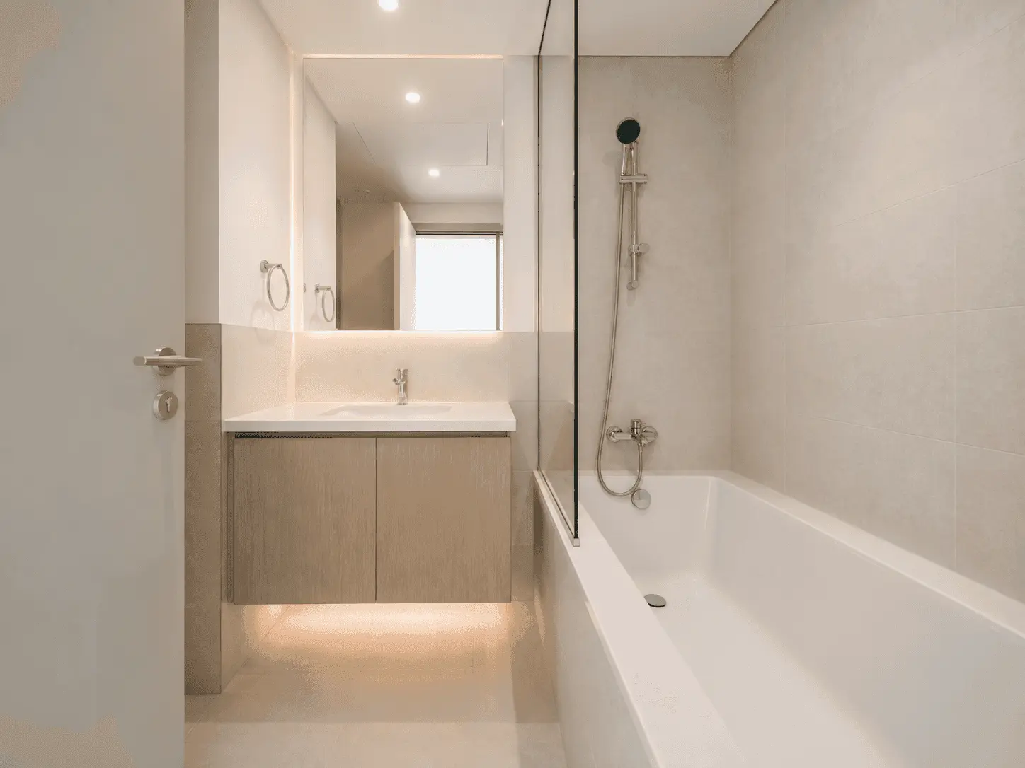 Bathroom renovation with built-in bathtub, glass screen, backlit mirror and floating vanity in Creek Harbour apartment