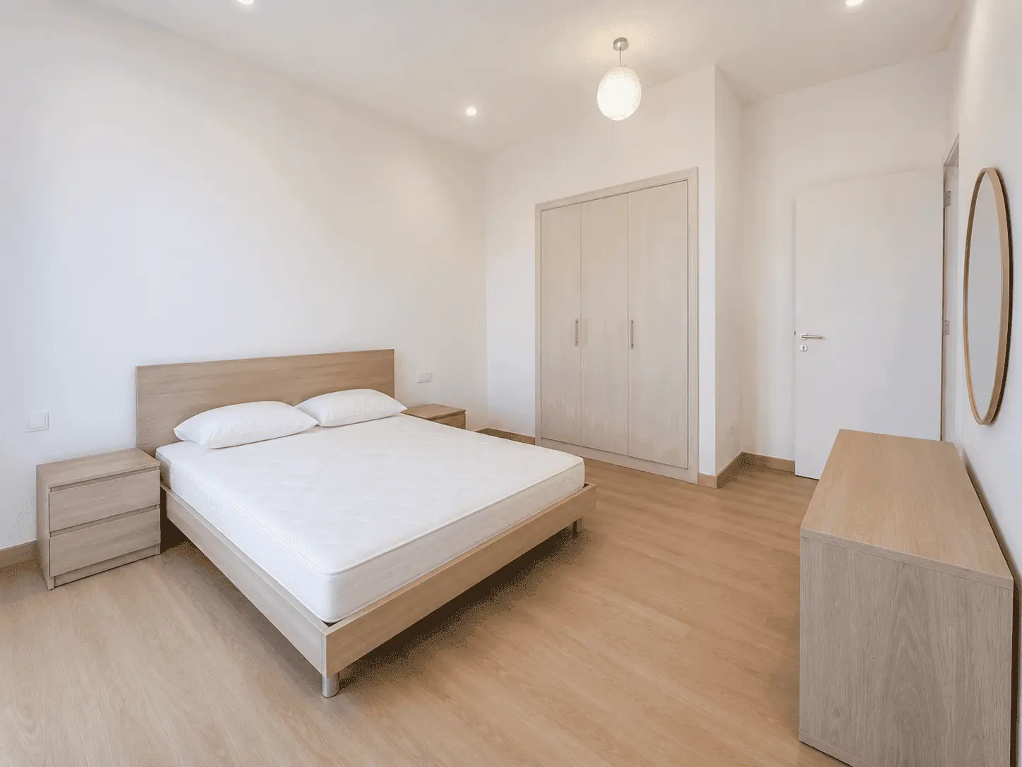Third bedroom renovation with oak bed, built-in wardrobes and round mirror in Victory Heights villa, Dubai