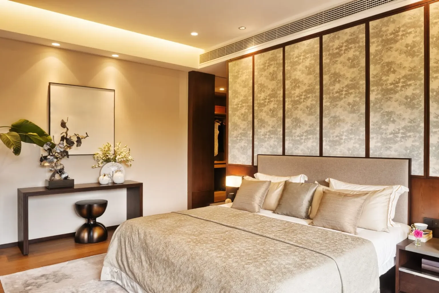 Master suite with framed fabric wall panels, concealed lighting and a built-in dressing area